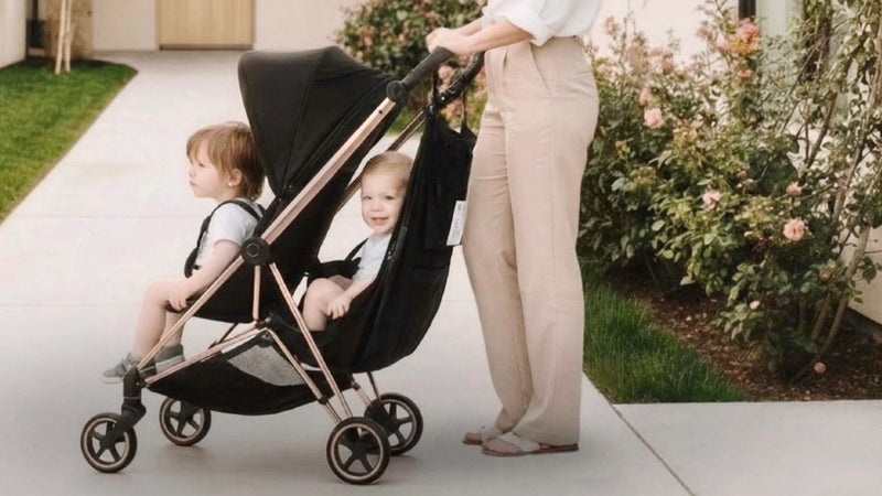 Mom pushing two toddlers with one child in the Black Fox Stroller Hammock Sling.